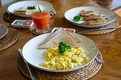 a table with plates of eggs and toast and a glass of orange juice at Villa Celeste by Villa Finder in Seminyak