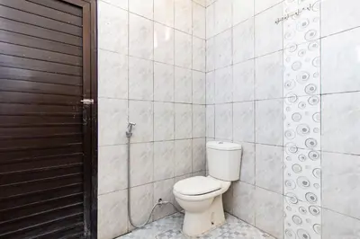 a bathroom with a toilet and a wooden door at SN Guest House Near Trans Studio Mall in Legian