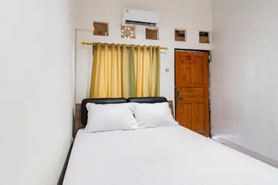 a bedroom with a white bed and a door at SN Guest House Near Trans Studio Mall in Legian