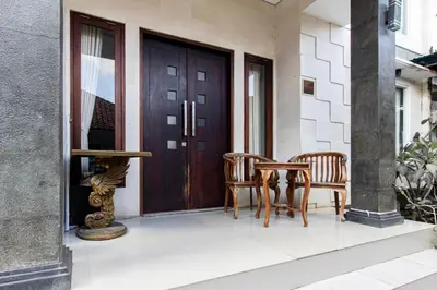 a porch with two chairs and a wooden door at SN Guest House Near Trans Studio Mall in Legian