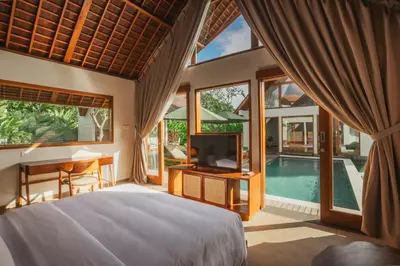 a bedroom with a bed and a tv and a pool at Arpana Luxury Private Pool Villas in Jimbaran