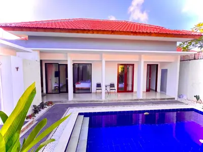 a villa with a swimming pool in front of a house at Villa Majegau 4 Seminyak in Seminyak