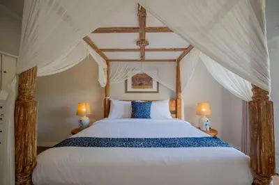 a bedroom with a canopy bed with two lamps at Deja Blu Villa in Seminyak