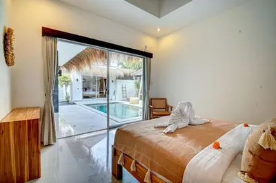 a bedroom with a bed and a sliding glass door at Villa Esha II in Seminyak