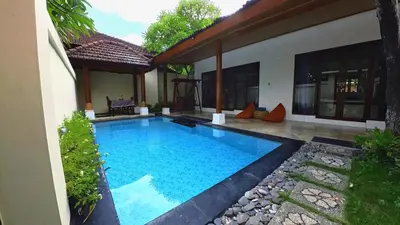 a swimming pool in front of a house at Privat Pool villa at kuta in Kuta