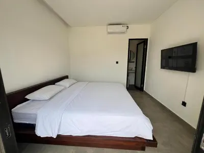 a bedroom with a large bed with white sheets and pillows at Uger House Seminyak in Seminyak