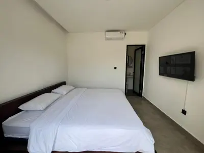 a bedroom with a white bed and a tv at Uger House Seminyak in Seminyak