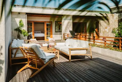a patio with a couch and chairs on a deck at The Urban Retreat Seminyak Private Pool Villas with Butler for Families & Groups in Seminyak