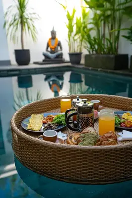 a tray of breakfast food on a table next to a pool at Cozy 2 beds villa in Seminyak in Seminyak
