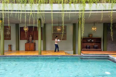 a woman standing on a stage next to a swimming pool at Janya 3 BR Private Pool Villa ZN158 in Canggu