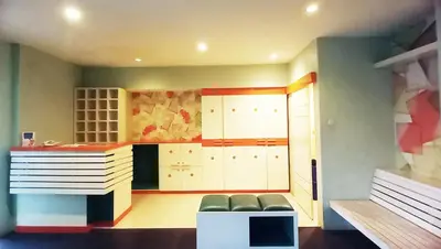 a kitchen with white cabinets and a couch in a room at Harris Hotel & Residences Kuta in Kuta