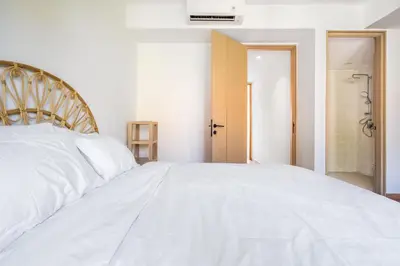 a bedroom with a white bed and a bathroom at IRMAS Villa Bali in Seminyak