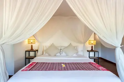 a bedroom with a white bed with white drapes at Villa Waterlily by Villa Finder in Seminyak