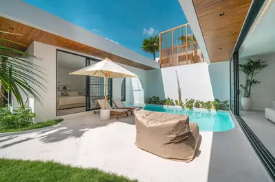 a patio with a pool and an umbrella at Villa Jenna - Exquisite 3BR Villa Close to Batu Belig Beach in Canggu