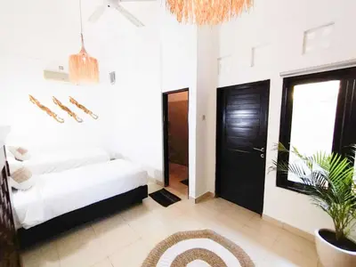 a white room with a bed and a potted plant at Salt Hideaway - 2 BR apartment, central Seminyak in Seminyak