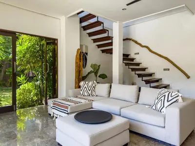 a living room with a white couch and stairs at Villa Blubambu in Seminyak
