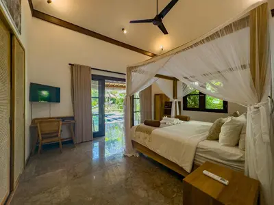 a bedroom with a canopy bed and a desk at Villa Blubambu in Seminyak