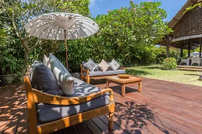 two chairs and an umbrella on a wooden deck at Bali Villa Home in Seminyak