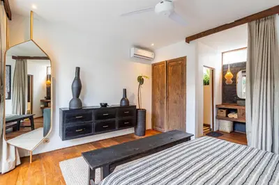a bedroom with a bed and a dresser and a mirror at Villa Elita - Modern Stylish 4BR Villa with Rooftop Lounge, 12 Minutes to the Beach in Kerobokan