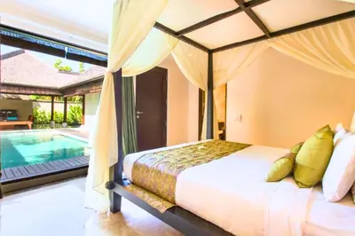 a bedroom with a bed and a swimming pool at Dilana 2 BR Bamboo Villas JU66 in Seminyak