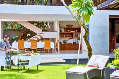 a man cooking food on a table in a garden at Neada 4 BR Grand Pool Villa JU68 in Seminyak