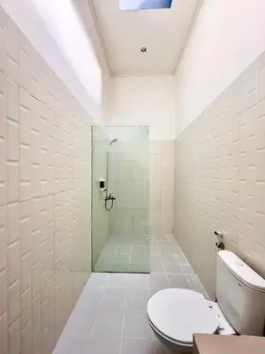 a white bathroom with a shower and a toilet at Bali Stuti Jimbaran Inn in Jimbaran