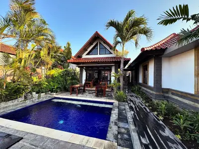 a house with a swimming pool in front of a house at Bali Stuti Jimbaran Inn in Jimbaran
