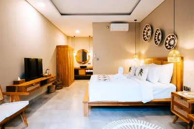 a bedroom with a white bed and a television at Villa Koura Kuta in Kuta