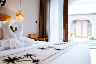 a bedroom with a white bed with a large window at Villa Koura Kuta in Kuta