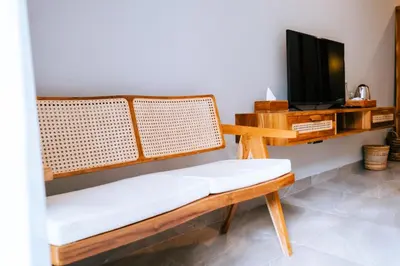 a living room with a bench and a tv at Villa Koura Kuta in Kuta