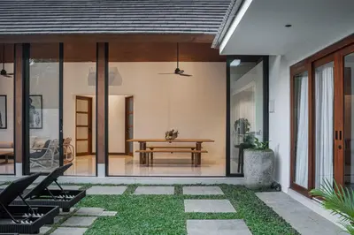 a pivot house with glass doors and a table at Villa Under the Sun - Seminyak in Seminyak