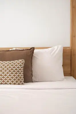 a bed with white pillows and a wooden headboard at Villa Under the Sun - Seminyak in Seminyak