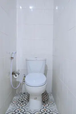 a white toilet in a bathroom with a tile floor at MIMU C-O Living in Kerobokan