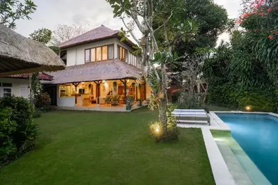 a house with a swimming pool in front of a yard at Villa Pande Sanur Beach Side in Sanur