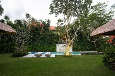 a backyard with a swimming pool with two benches at Villa Pande Sanur Beach Side in Sanur