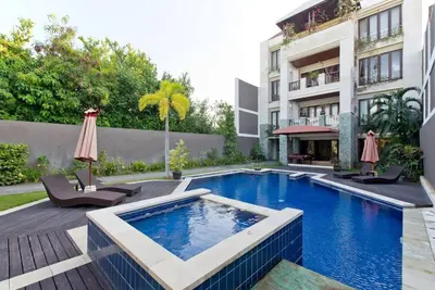 a swimming pool with two chairs and a building at Quiet Central Seminyak 2bd 2 bath and walk to eat st in Seminyak