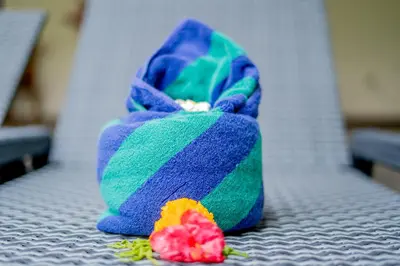 a purple and green bag and a flower on a bed at Villa Catalina Seminyak in Seminyak