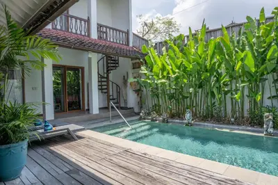 a swimming pool in front of a house with plants at Villa Catalina Seminyak in Seminyak