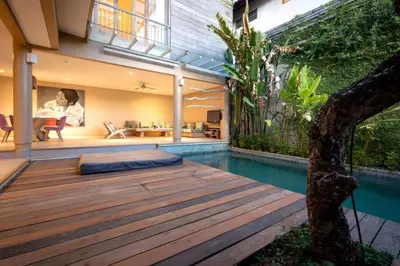 a house with a wooden deck next to a swimming pool at Villa Ewa 1 in Seminyak