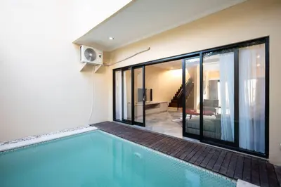 a swimming pool next to a house with a balcony at Villa Uma Sari c9 in Seminyak