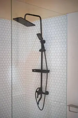 a shower with a black shower head on a wall at Villa Uma Sari c9 in Seminyak