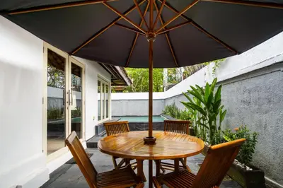 a wooden table and chairs with an umbrella on a patio at Villa Putri Mila in Seminyak