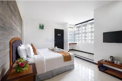 a hotel room with a bed and a television at The Kanjeng Suites Kuta Galeria - Bali in Kuta