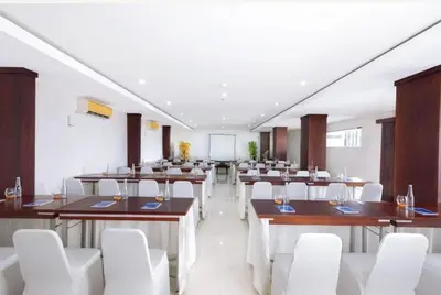 a large room with tables and white chairs at The Kanjeng Suites Kuta Galeria - Bali in Kuta