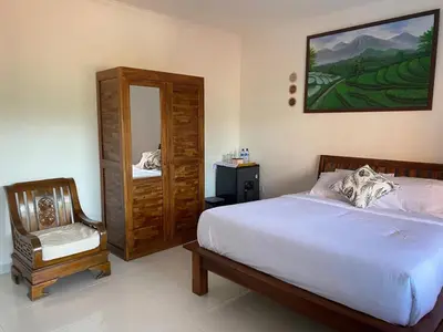 a bedroom with a bed and a mirror and a chair at Manis Guest House in Seminyak