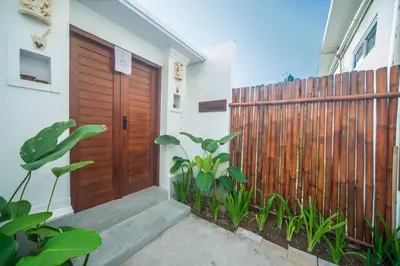 a house with a wooden door and a fence at Villa Semangka, Seminyak Umalas in Kerobokan
