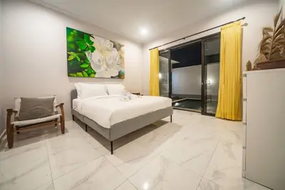 a bedroom with a bed and a chair at Villa Semangka, Seminyak Umalas in Kerobokan