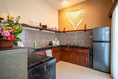 a kitchen with wooden cabinets and a stainless steel refrigerator at Villa bella wilson II in Seminyak