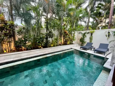 a swimming pool with two chairs and palm trees at Classic tropical villa with private pool in Umalas in Dalung