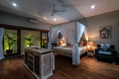 a bedroom with a canopy bed and a chair at Classic tropical villa with private pool in Umalas in Dalung